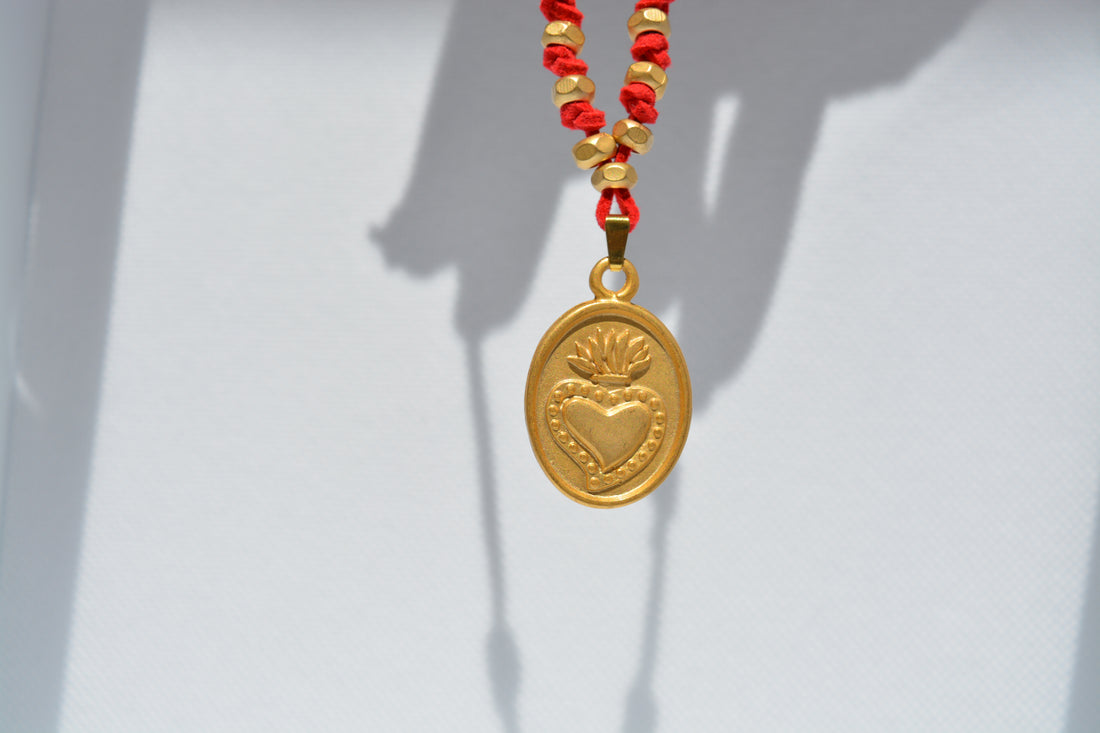 Collana cuore sacro dorato su cordoncino rosso