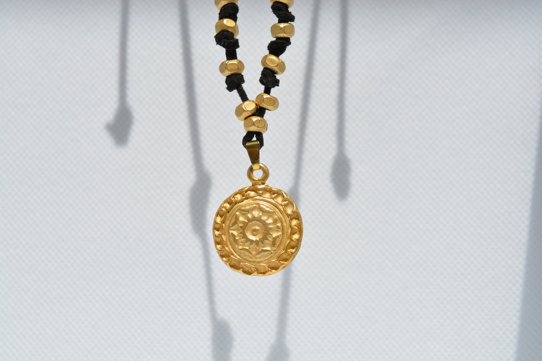 Collana nera con ciondolo dorato inciso